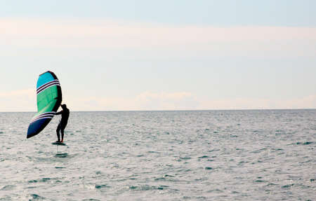 Man practicing wing foil with hydrofoil at sunset in the seaの写真素材
