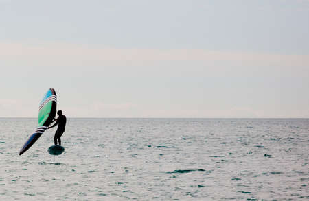 Man practicing wing foil with hydrofoil at sunset in the seaの写真素材