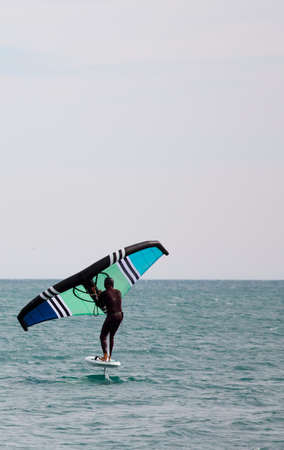 Man practicing wing foil with hydrofoil at sunset in the seaの写真素材