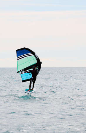 Man practicing wing foil with hydrofoil at sunset in the seaの写真素材