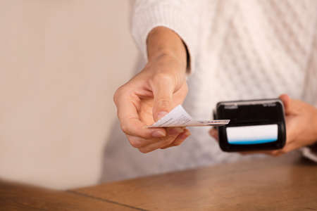 Young woman doing process payment with the bill or invoice on the POS cash terminal in a shop, finance concept, Focus in the hand.の写真素材