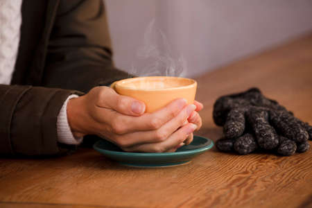 She warms her hands with a cup of hot coffee.の写真素材