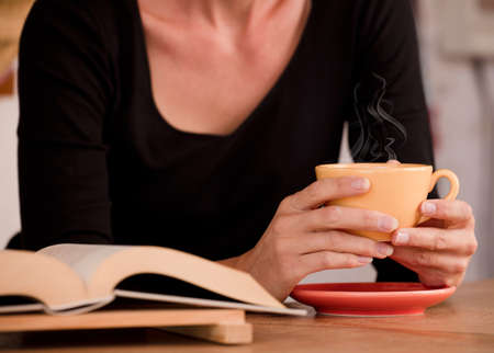 Female hands hold a yellow cup with coffee. Focus on the cupの写真素材