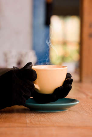 yellow cup with hot coffee, in the hands of a woman with gloves, very cold day. Focus on the cup.の写真素材
