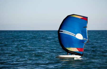 A man leaves the beach of El Palo in Malaga, riding a paddle board with a hydrofoil.の写真素材