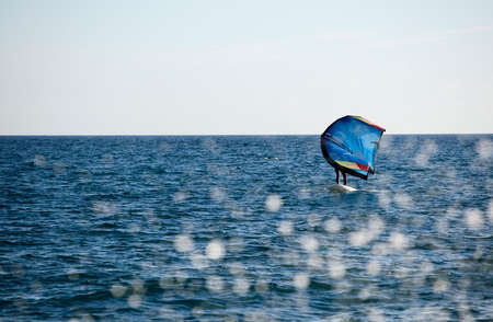 rider with wing foil sails through the sea and splash of water drops jump into the seaの写真素材
