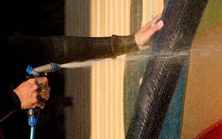 man cleans wingfoil sports equipment, with pressurized water hoseの写真素材