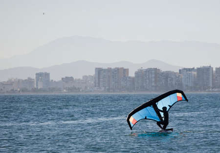 young man with wingfoil on the beachの写真素材