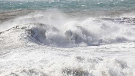 big waves breaking on the shore, with white foamの写真素材