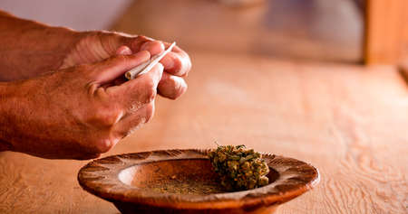 man hands prepare marijuana cigar at homeの写真素材