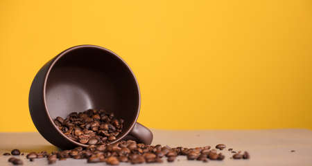 brown cup with coffee and roasted coffee beans, with yellow backgroundの写真素材