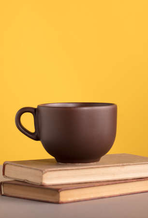 brown cup with coffee or chocolate, on books, with yellow backgroundの写真素材