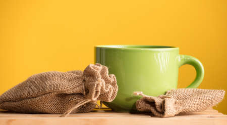 green mug with raffia sacks with yellow backgroundの写真素材