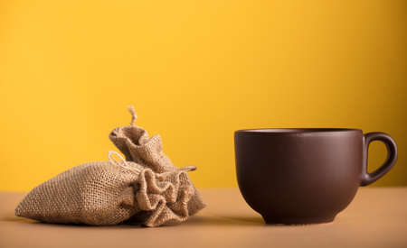 brown cup of chocolate or coffee, raffia sacks with yellow backgroundの写真素材