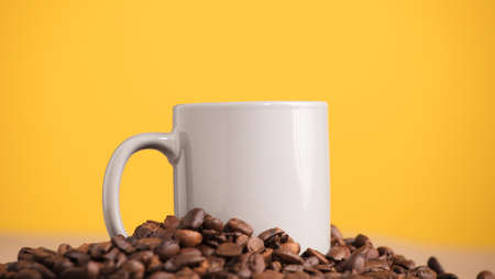 light gray mug, on a mountain of coffee beans, with yellow backgroundの写真素材