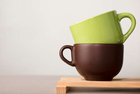 two brown and green cups of coffee or tea on wood with white backgroundの写真素材