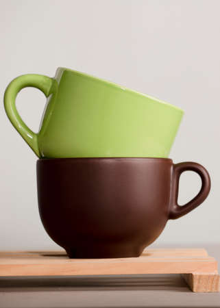 two brown and green cups of coffee or tea on wood with white backgroundの写真素材