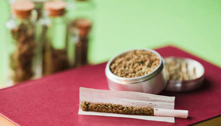chopped marijuana, on cigarette paper with filter and airtight glass bottle, process for the production of pure marijuana. Red backgroundの写真素材