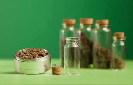 marijuana on grinder, glass jars on table, with dark green background.の写真素材