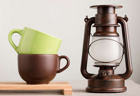 two brown and green cups of coffee or tea on wood with lamp and white backgroundの写真素材