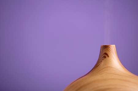 Essential oil air freshener in wood with steam, with a violet background (very peri).の写真素材