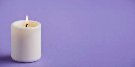 candle with flame, violet background space for textの写真素材