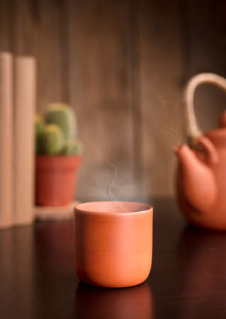 cup of coffee or tea on wooden table, with teapot, books, brown wooden background.の写真素材