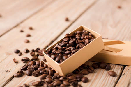 roasted coffee beans in yellow gift box with bow on wooden table