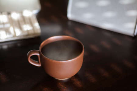 brown cup of coffee, with hot steam, on the work deskの写真素材