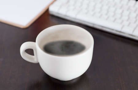 white cup coffee, with hot steam, on the work desk.の写真素材