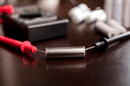 battery, volt meter, red positive pole, black negative pole, on work table.の写真素材