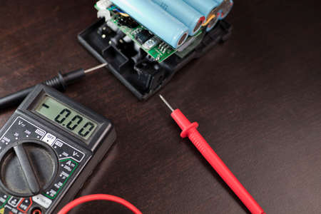 volt meter battery 18650, red positive pole, black negative pole, on work table.の写真素材