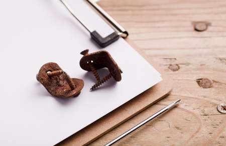 metal angle square with corrosive rust and screws, on a workbook, on top of a wooden work tableの写真素材
