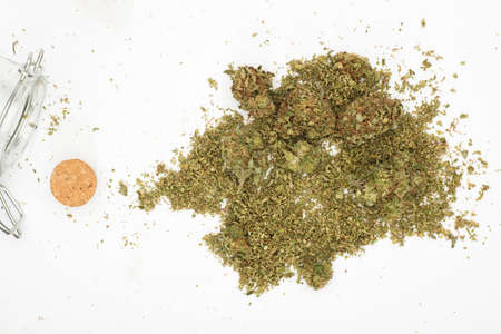 top view of marijuana buds with grinder accessories, glass bottles, and white backgroundの写真素材