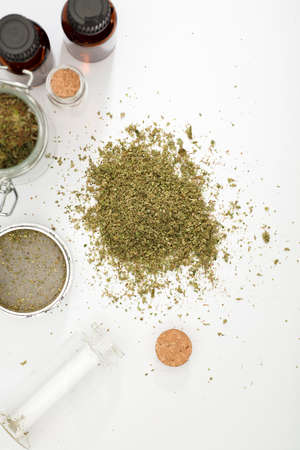 top view of marijuana buds with grinder accessories, glass bottles, and cans of cane oilの写真素材