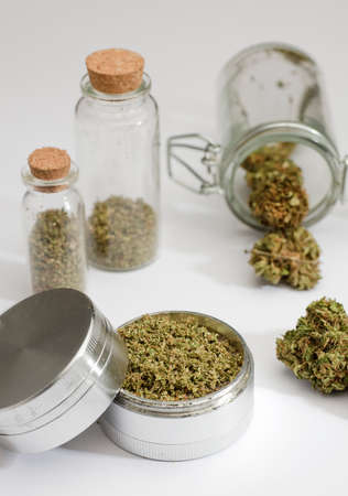 grinder with ground marijuana inside, buds, glass bottle with cork stopper, white backgroundの写真素材