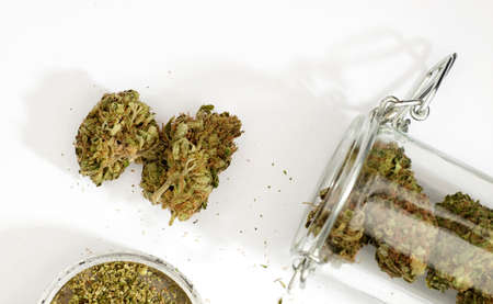 marijuana buds, partial view of grinder and hermetic glass jar for storage, white background.の写真素材