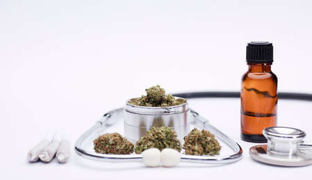 grinder with marijuana buds on top, joint, phonendoscope, with white background, space for text.の写真素材