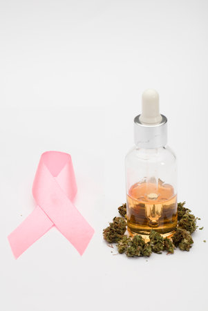 cancer pink ribbon with CBD (Cannabidiol) oil with bottle and dropper and buds, cancer treatment, natural medicine on a white background. CBD isolated hemp oil. THC free.の写真素材