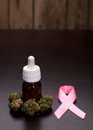 Medical marijuana buds with oil bottle, brown background. The pink ribbon, an international symbol of breast cancer awareness and moral support for women. Isolated background, copy spaceの写真素材