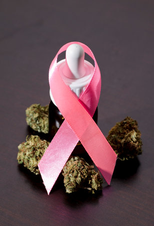 pink ribbon symbol fight cancer with bottle of oil, and marijuana buds, on brown wooden table.の写真素材