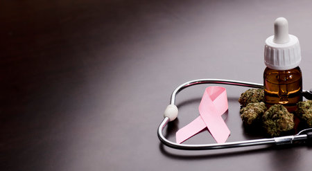 cancer pink ribbon with medical marijuana buds, stethoscope, oil bottle, brown background.の写真素材