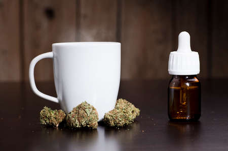marijuana buds oil drop dispenser, and white cup, dark wood backgroundの写真素材