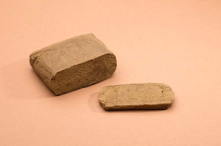 hashish tablet cut out next to large 100 gram portion, brown backgroundの写真素材