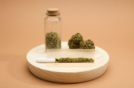 preparation of marijuana cigarette, with glass bottle. on wood with buds, brown backgroundの写真素材