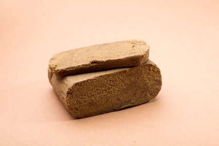 hashish tablet cut out next to large 100 gram portion, brown backgroundの写真素材