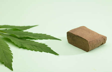 large portion hashish tablet with marijuana leaf, green backgroundの写真素材