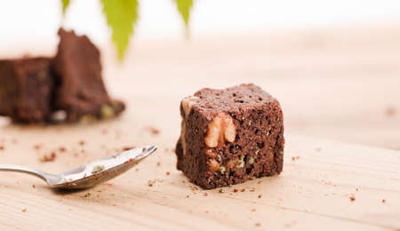 Chocolate cupcake muffins with cannabis buds. Marijuana hemp in food dessert. Chocolate herb muffins cooking. Marijuana cake on a brown wooden table. green marijuana leaf in the backgroundの写真素材