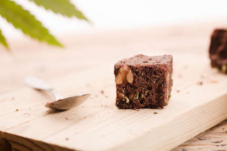 Chocolate cupcake muffins with cannabis buds. Marijuana hemp in food dessert. Chocolate herb muffins cooking. Marijuana cake on a brown wooden table. green marijuana leaf in the backgroundの写真素材