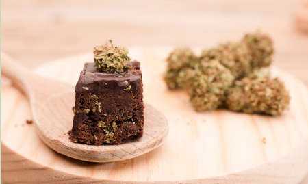 Chocolate cupcake muffins with cannabis buds. Marijuana hemp medical drugs in food dessert. Chocolate herb muffins cooking. Marijuana cake on a brown wooden table.の写真素材